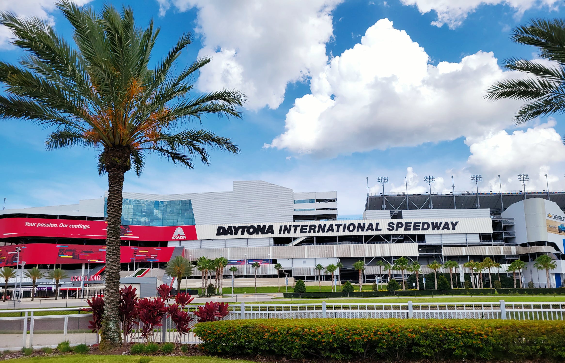 Daytona International Speedway on a sunny day, symbolizing thrilling racing action amidst warm weather and a palm tree, a quintessential Florida experience.